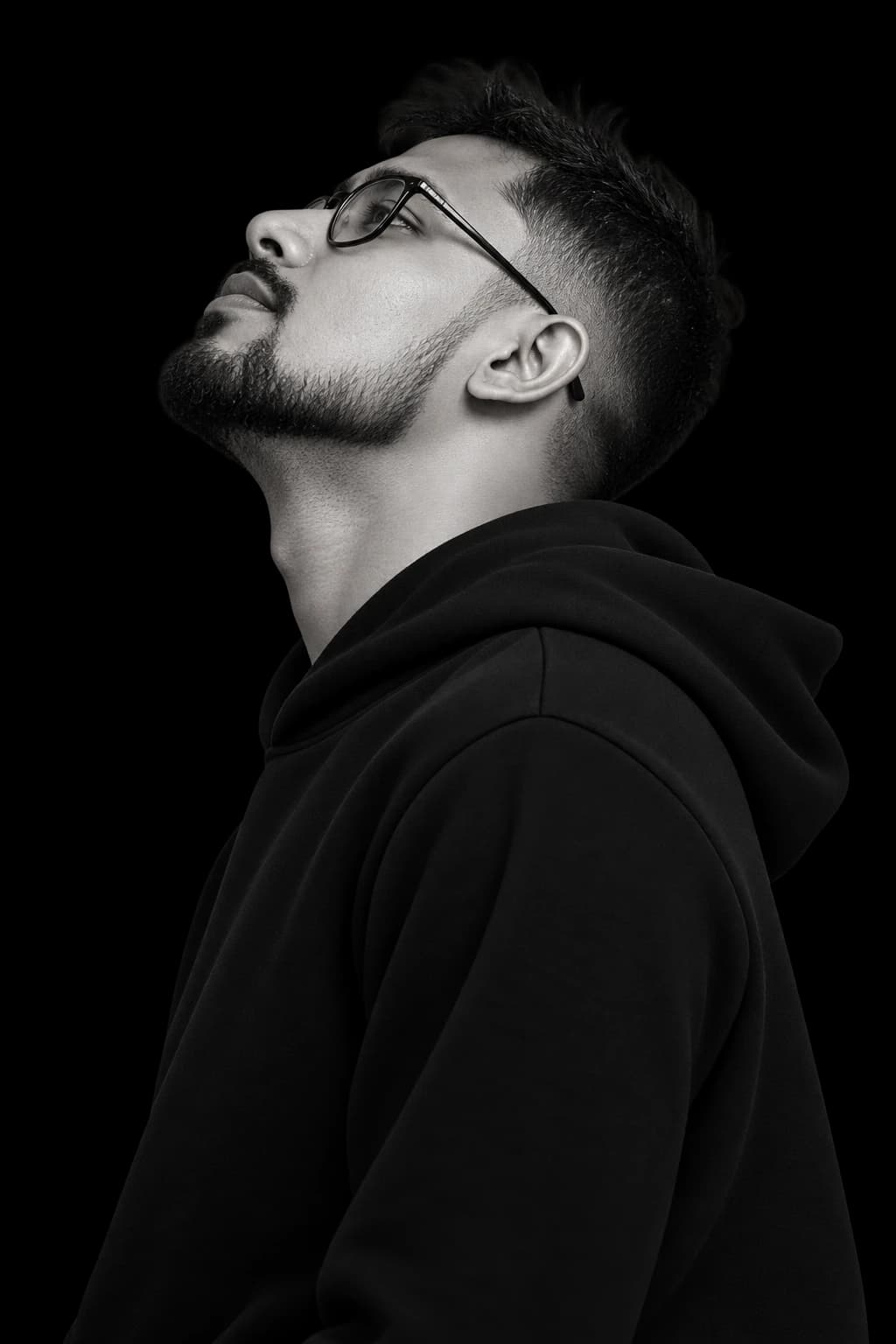Black and white portrait of Nuwan Shanaka wearing a hoodie and looking upward